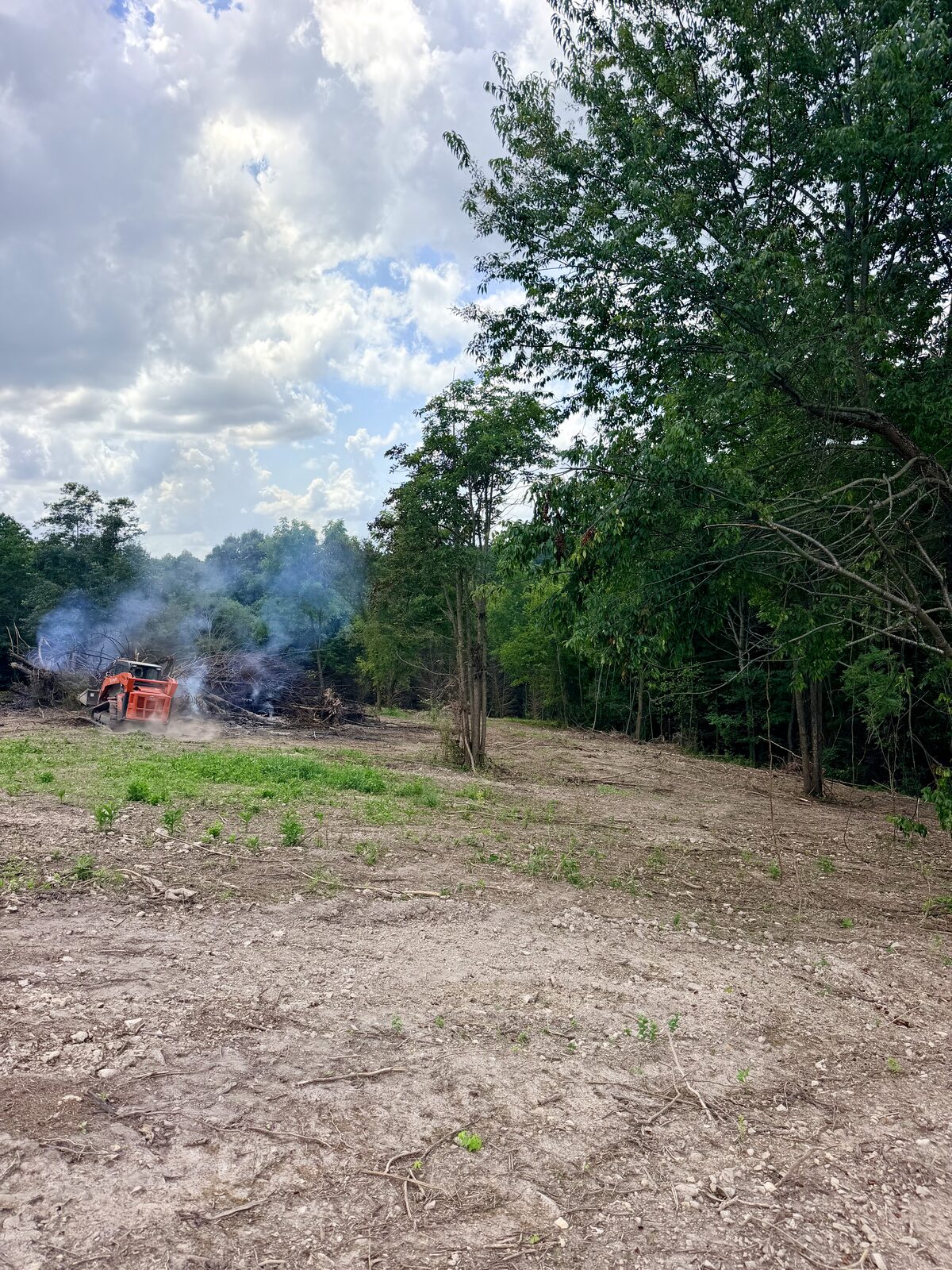 Freshly cleared acreage in Northwest Arkansas with a brush pile burning